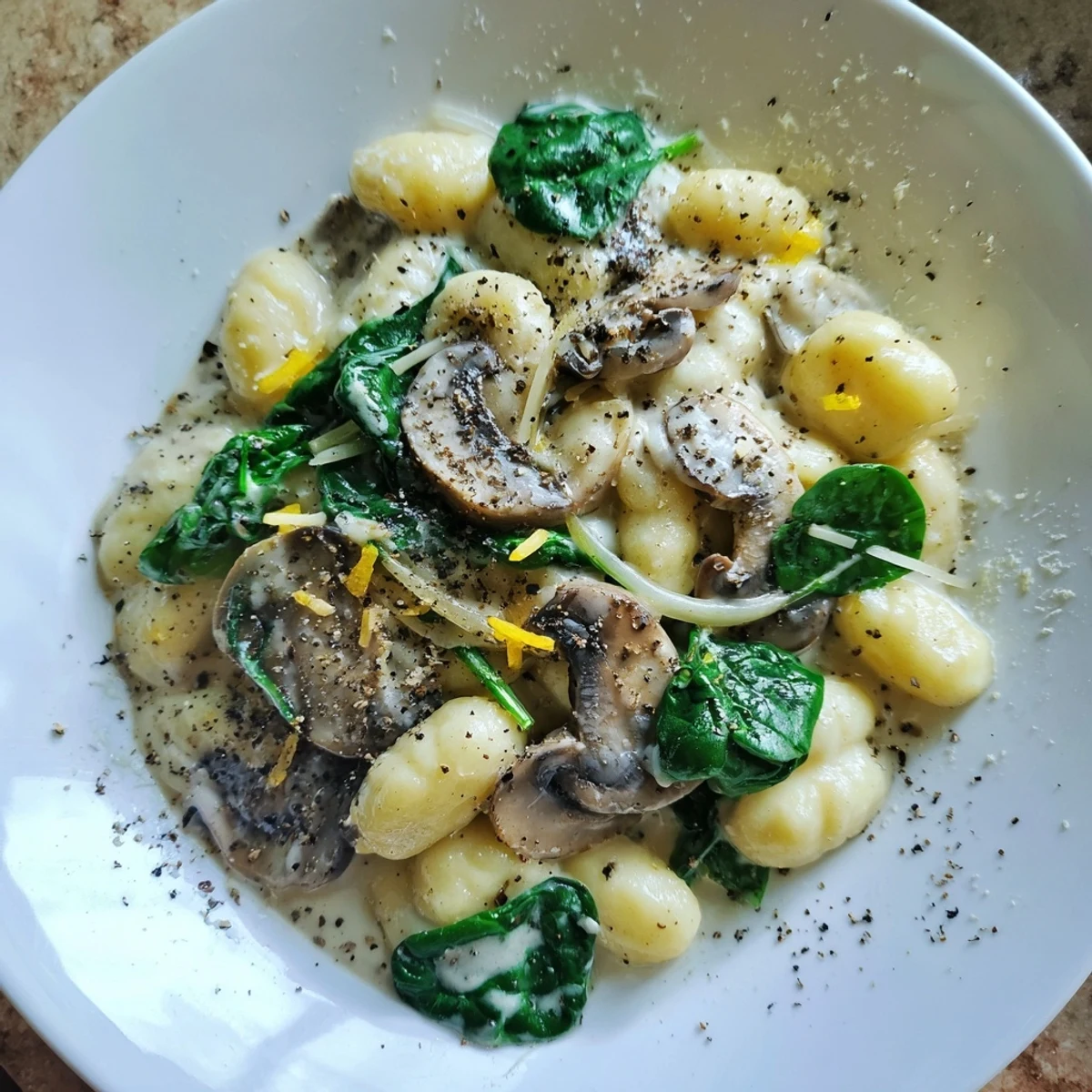 A close-up of creamy One-Dish Mushroom and Spinach Gnocchi, ready to serve with Parmesan cheese.