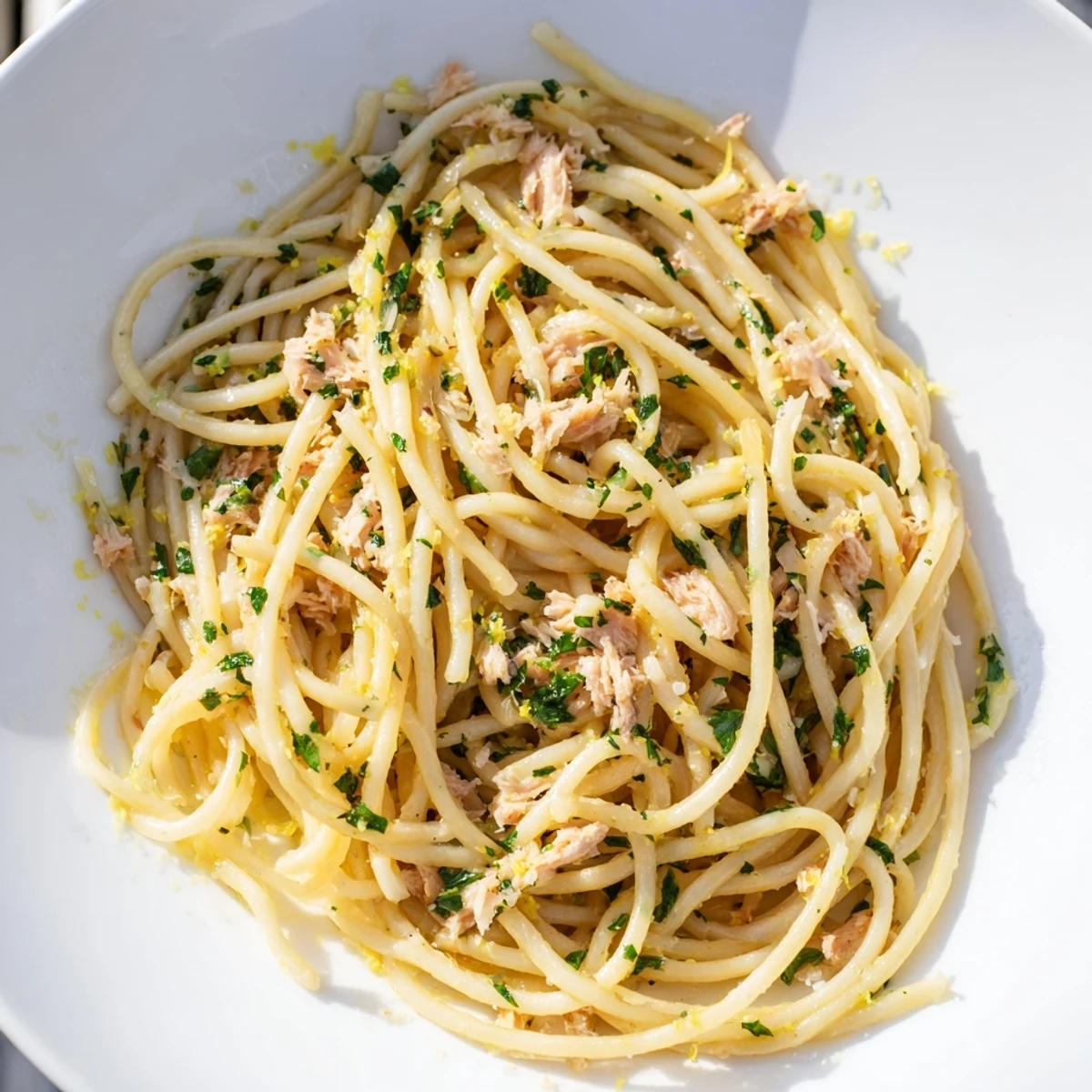 A generous serving of Lemon-Garlic Tuna Spaghetti in a bowl, ready to enjoy with a lemon wedge.