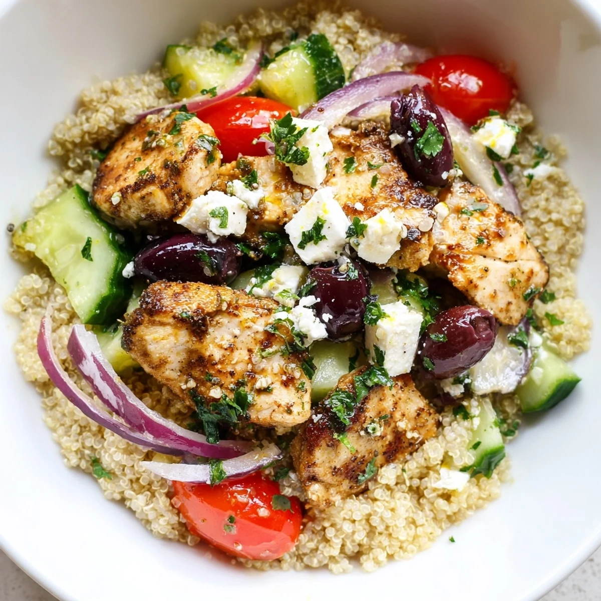 Juicy grilled chicken, fluffy quinoa, crisp cucumbers, olives, feta, and chickpeas topped with lemon-oregano dressing in a vibrant Mediterranean Chicken Bowl.  