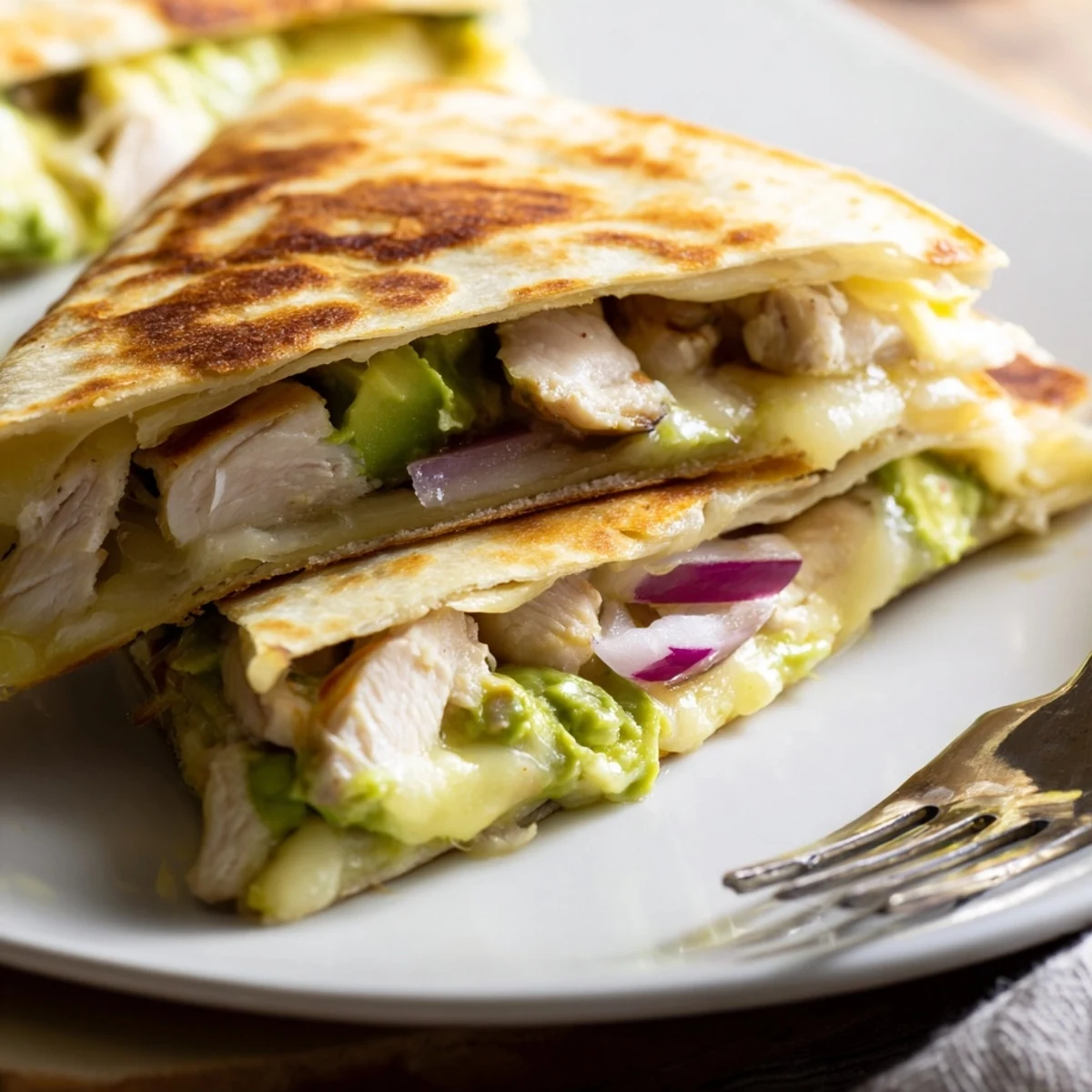 Freshly prepared Chicken Avocado Quesadilla featuring creamy avocado mash, juicy chicken, and melted cheese on a toasted tortilla.  