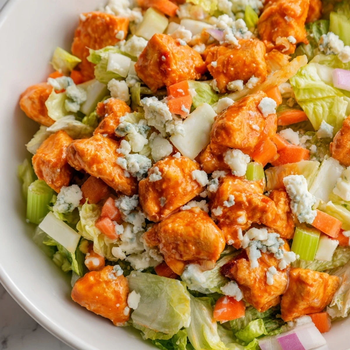 A vibrant Buffalo Chicken Chopped Salad features spicy buffalo chicken, crisp romaine, and creamy blue cheese crumbles.