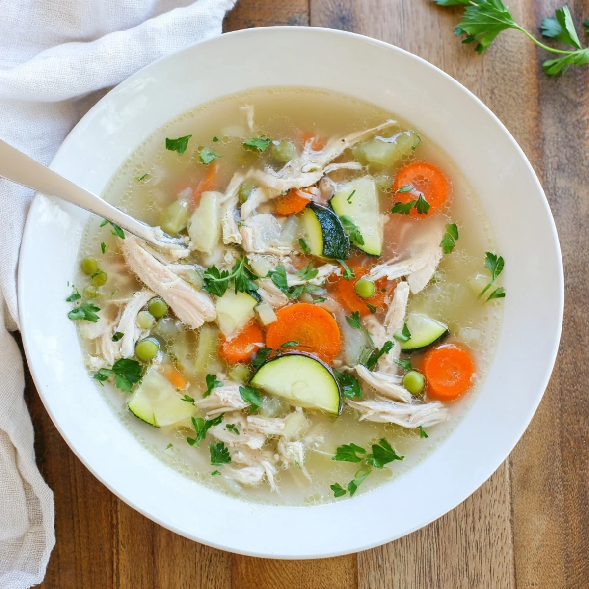 Bright Spring Garden Chicken Soup with tender shredded chicken, carrots, zucchini, and peas in a fragrant herb broth.