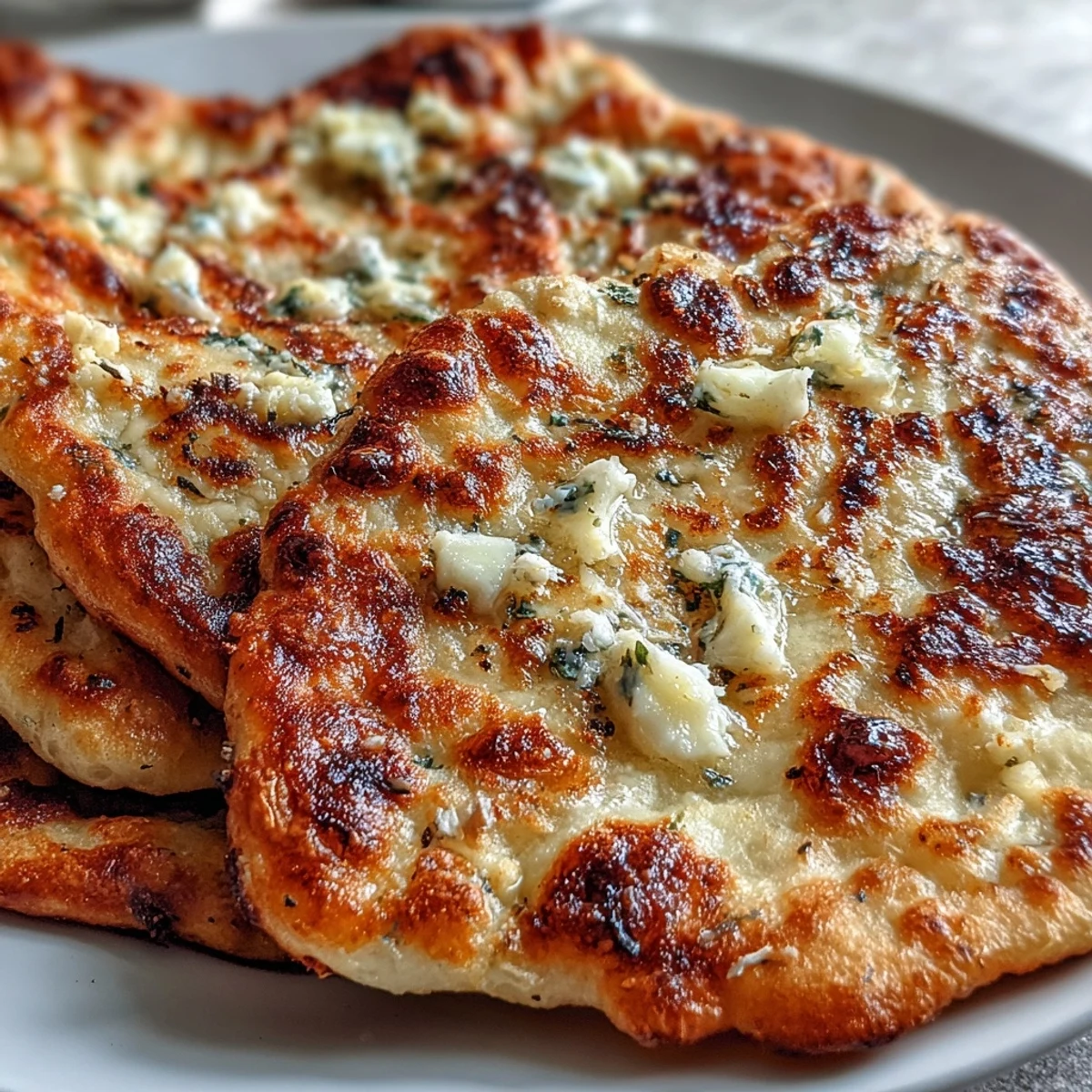 Freshly baked The Best Easy Garlic Naan Bread brushed with melted butter and minced garlic.