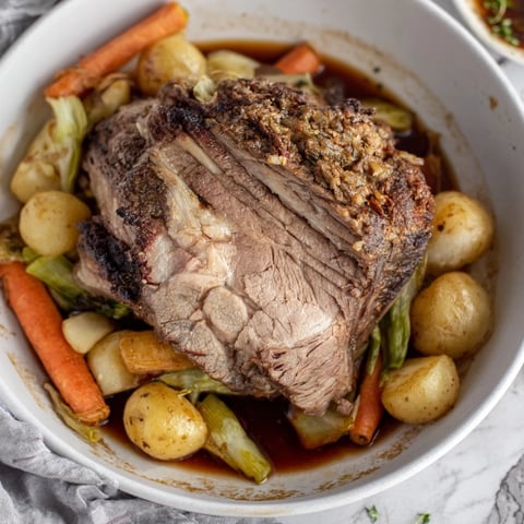 Fork-tender Slow-Roasted Beef Pot Roast, surrounded by colorful, soft root vegetables in a rich gravy.