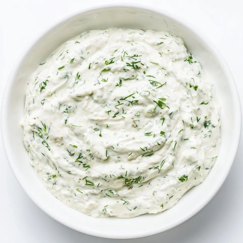 Creamy Greek Yogurt Herb Dip, speckled with fresh herbs, is ready to be scooped with crisp veggies.