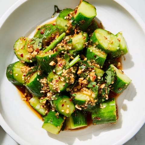 The Chinese Spicy Smashed Cucumber Salad glistens, tossed in a flavorful dressing with sesame seeds, ready to enjoy.