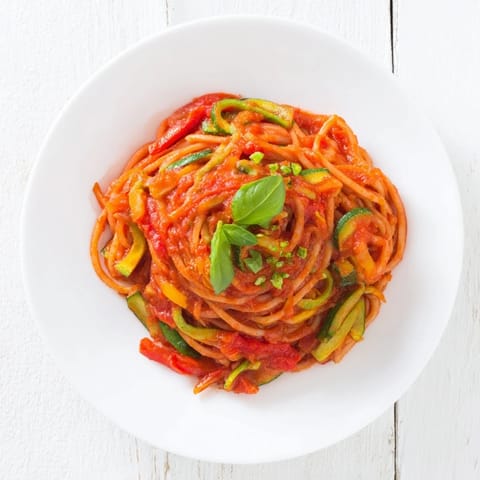 A steaming bowl of veggie-loaded tomato pasta sauce with fresh basil hints of Italian herbs.