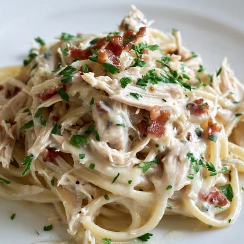 Heaping forkful of Chicken Carbonara featuring tender shredded chicken, al dente spaghetti, and rich egg sauce for a comforting meal.