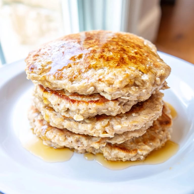 Warm and fluffy banana oat pancakes topped with fresh berries, perfect for a quick, healthy meal.