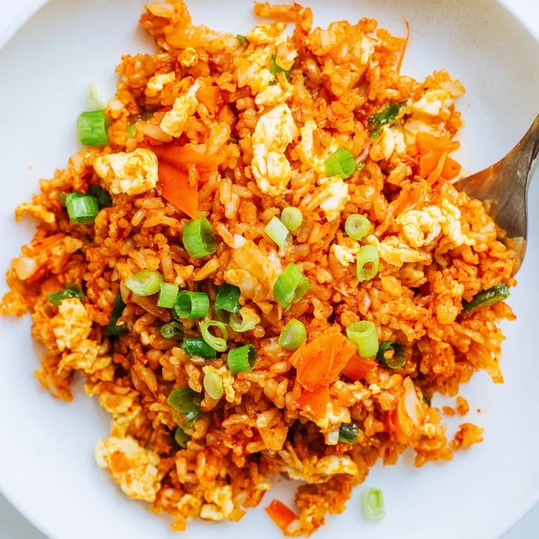 Close-up view of Spicy Kimchi Fried Rice in a hot skillet, showcasing vibrant red kimchi and scrambled eggs.
