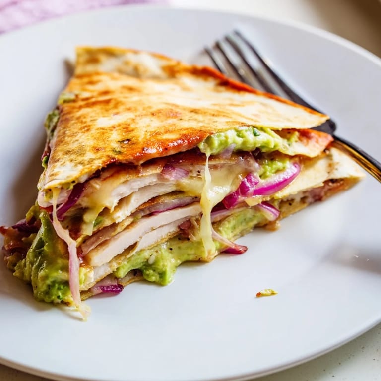 Close-up of a slice of Chicken Avocado Quesadilla revealing layers of tender chicken, avocado, and gooey Monterey Jack cheese.