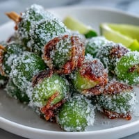 Frozen grape skewers coated in zesty lime sugar, a refreshing summer treat on wooden sticks.